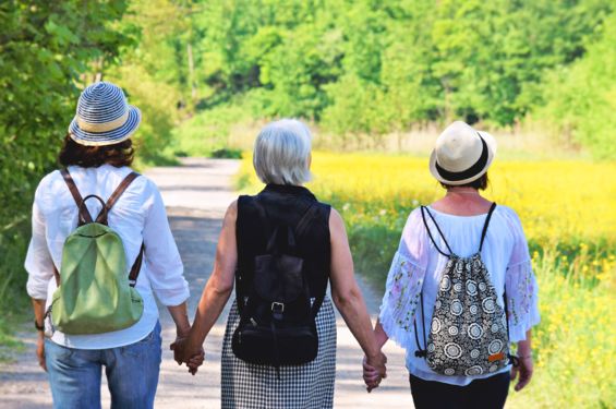 Drei Frauen halten sich an den Händen und gehen spazieren